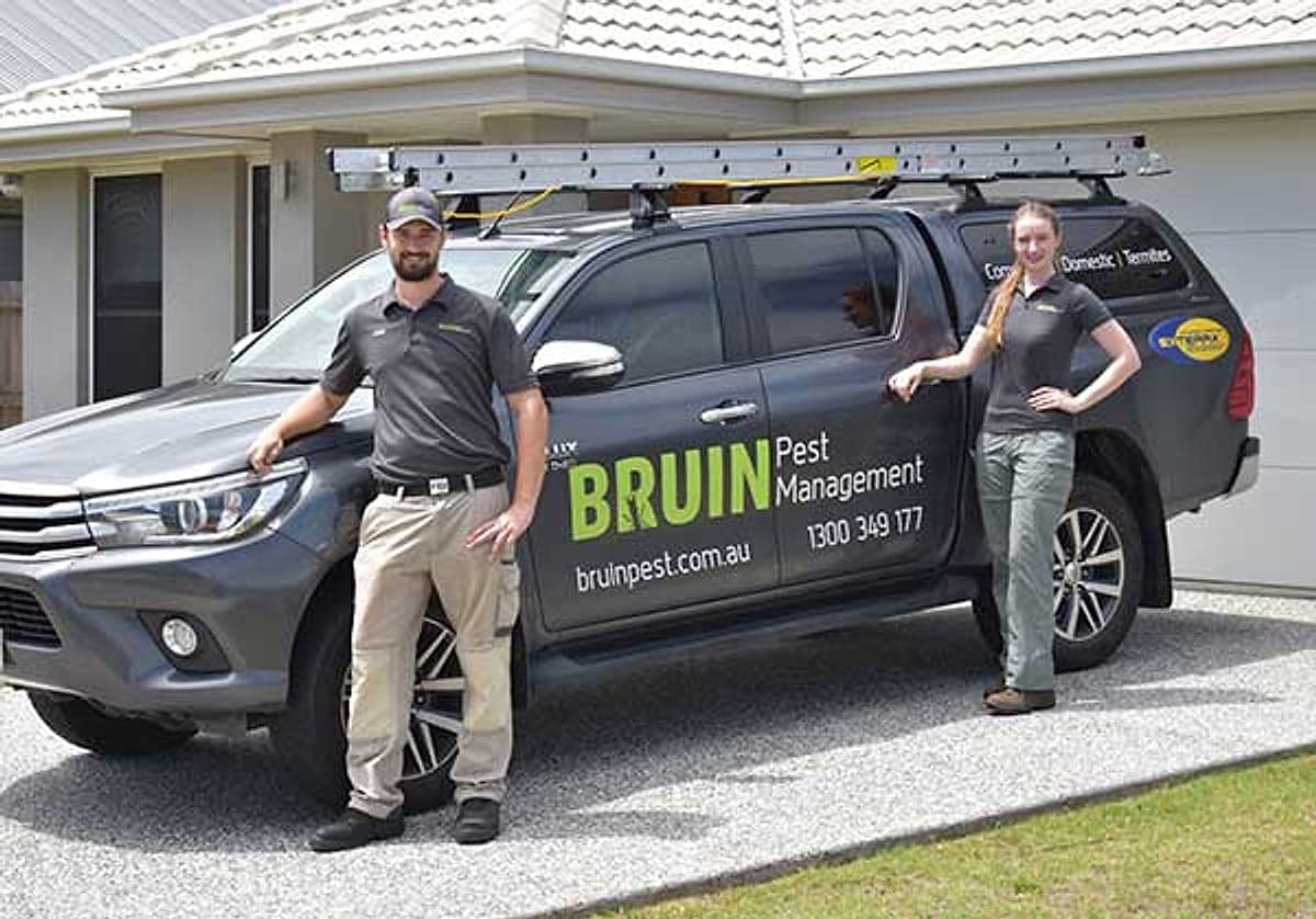 Bruin Pest Management technicians beside the branded work van outside a Brisbane home