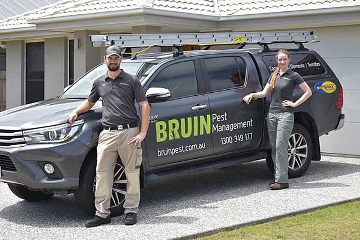 The Bruin Pest Management team beside their branded work van outside a Brisbane home
