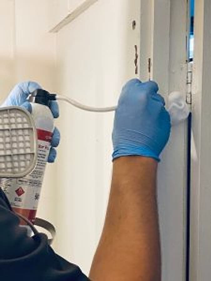 Bruin technician foaming a termite treatment into an affected timber frame