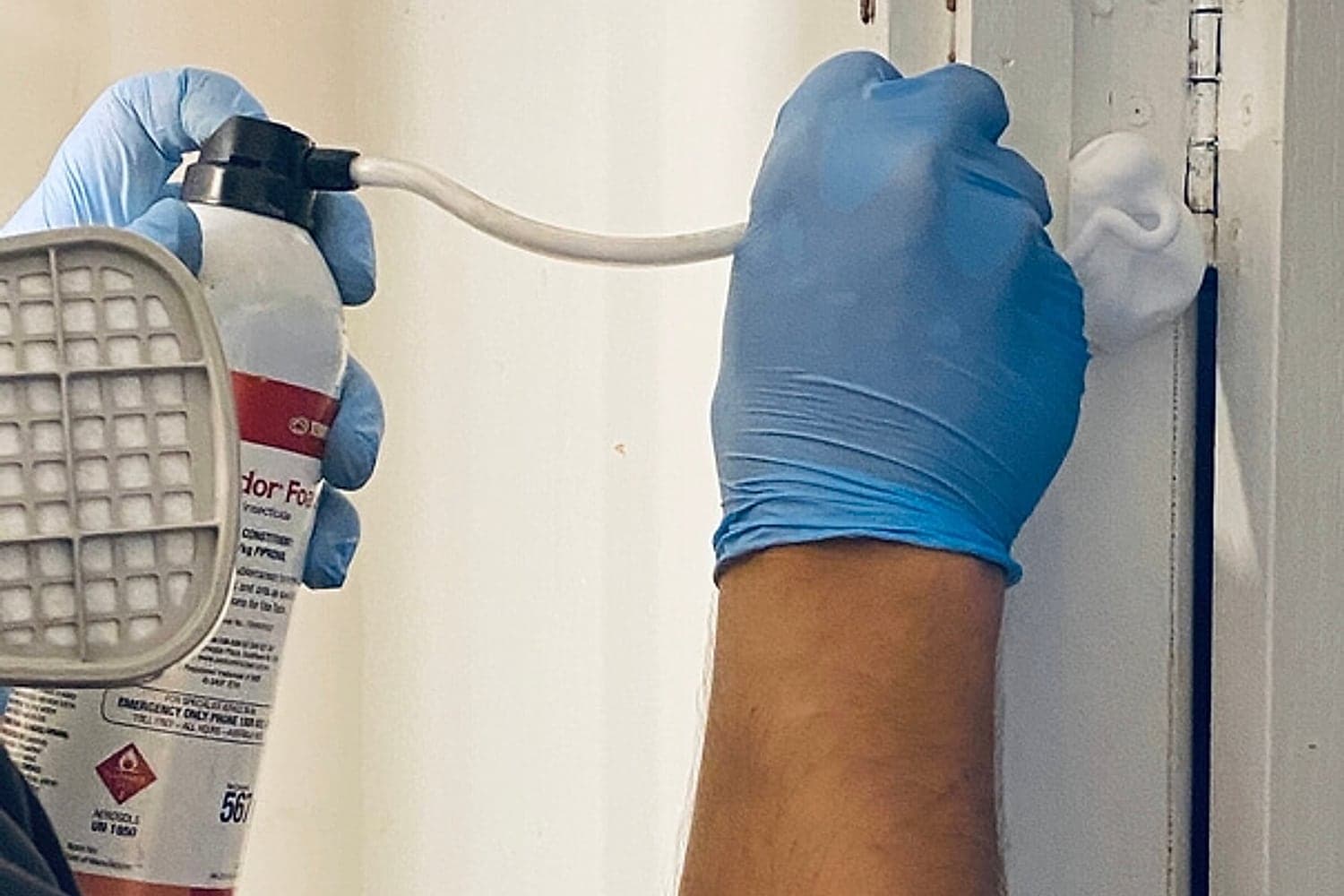 Bruin technician applying foam termite treatment into a wall cavity